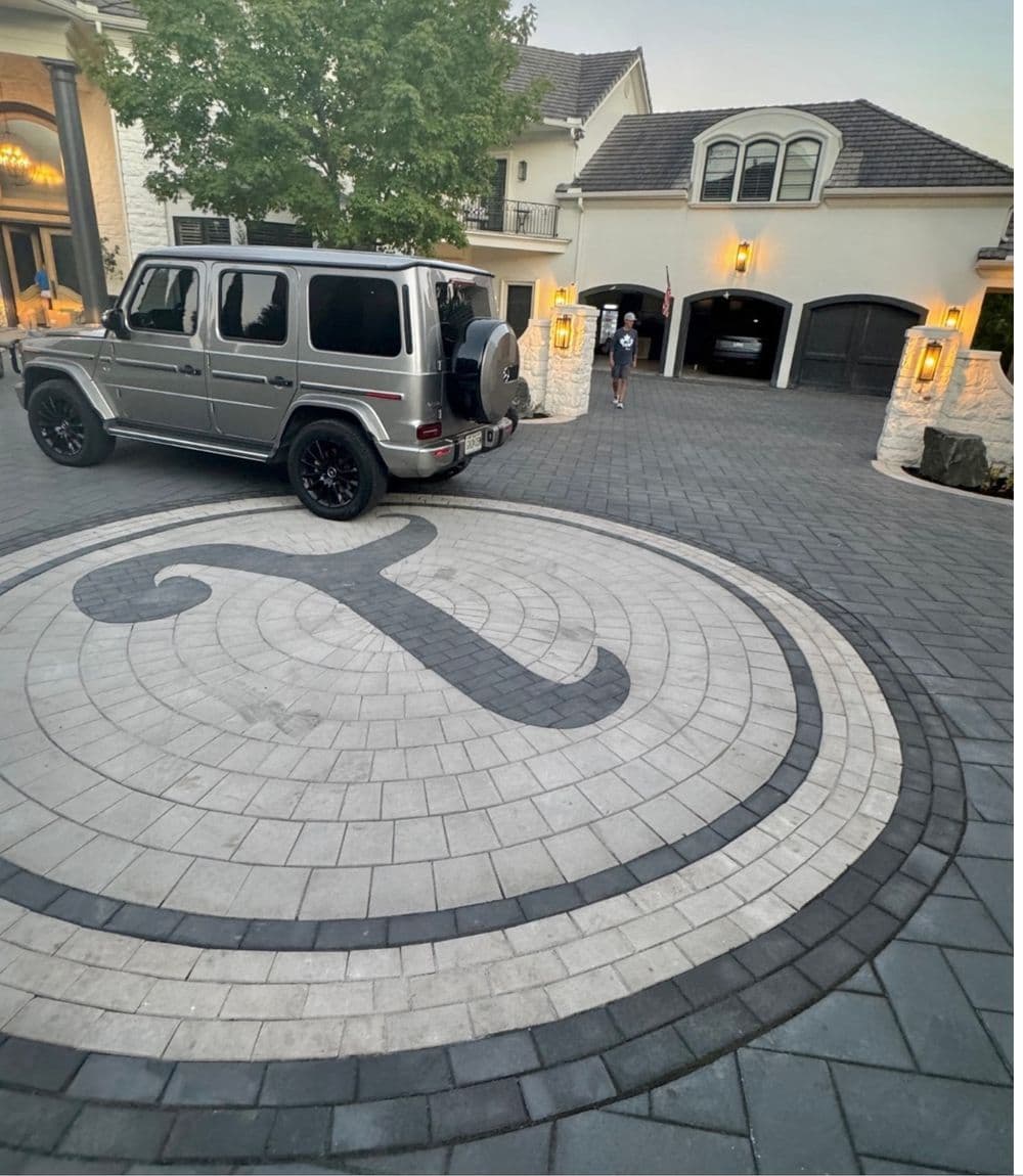 Luxury SUV parked on a stylish patterned driveway in front of an elegant house.