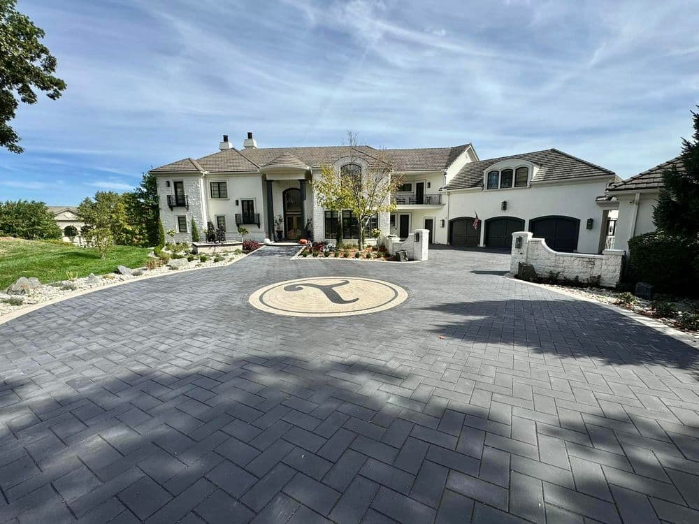Luxury home exterior with landscaped driveway featuring a prominent circular emblem.